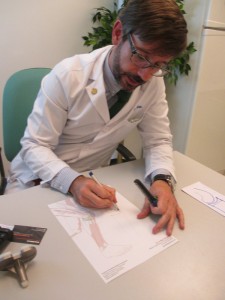 Doctor Alonso Bau, dibujando una rodilla con artrosis y explicando colocación de prótesis de rodilla